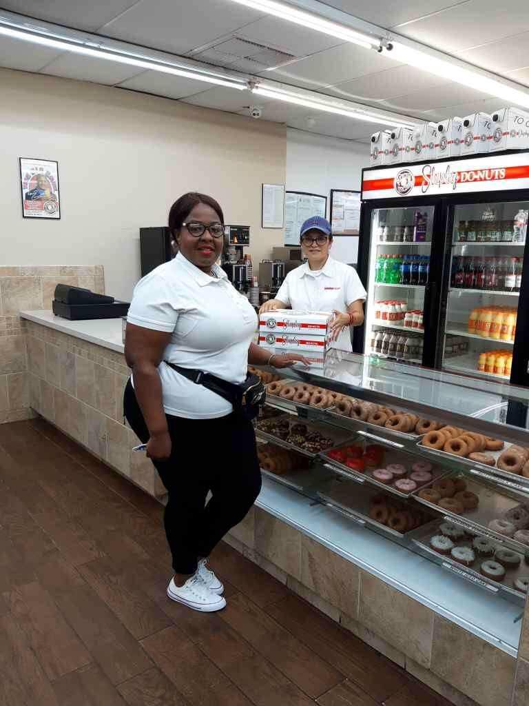 Donut shop employees behind display case