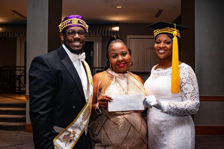 Three smiling adults in formal attire holding envelope