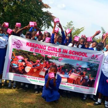 Schoolgirls holding banner and menstrual supplies