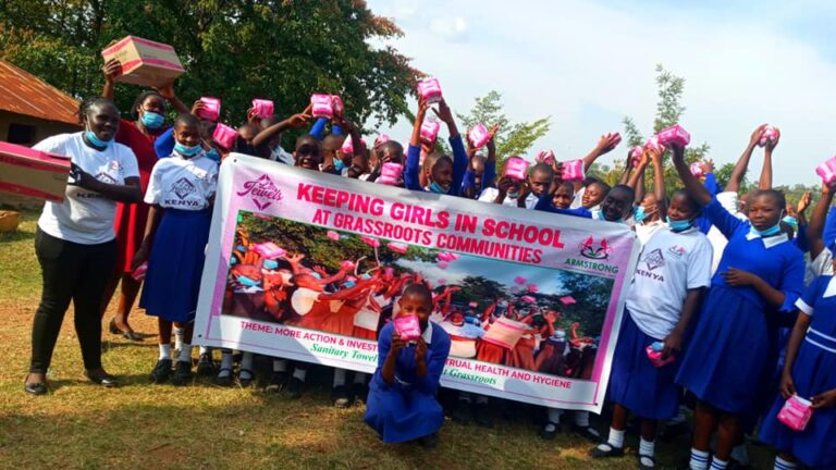 Schoolgirls holding banner and menstrual supplies