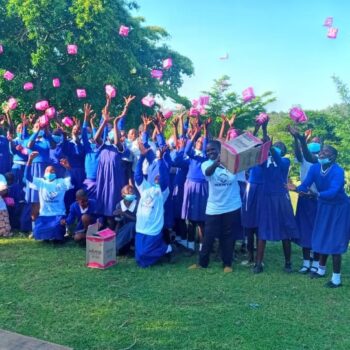 Group of students in blue uniforms celebrating outdoors